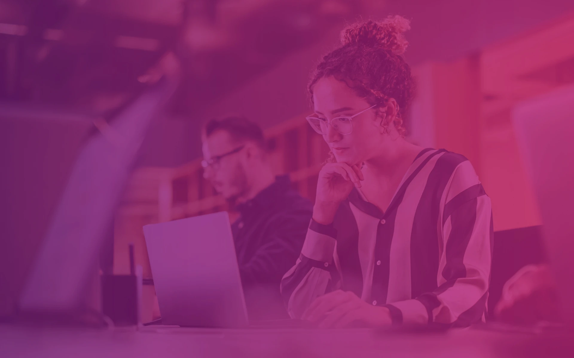 Graphic for section with all blogposts at Transition Technologies PSC website, woman and man by the laptops in the background with purple-pink gradient filter on it