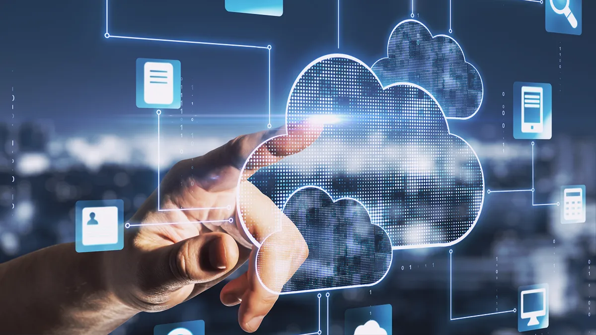 A hand interacting with a graphical representation of a cloud computing interface against a blurred cityscape background. The central cloud graphic is surrounded by various icons representing services like security, networking, and data storage, illustrating the concept of cloud computing and its connectivity to multiple services. Image for a blog article about ThingWorx AWS Connector.