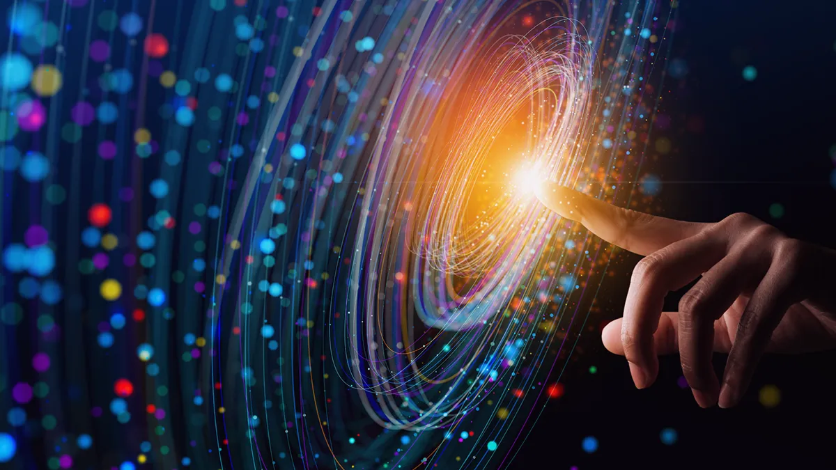 La photo montre une main avec l'index tendu. Une lumière vive se répand autour du bout du doigt, formant des cercles lumineux qui s'étendent de plus en plus loin - plus ils sont éloignés, moins ils sont visibles. La photo montre également de petits points colorés concentrés le long des lignes des cercles. D'après le contexte, il semble s'agir de l'immensité des nouvelles possibilités offertes par la technologie - une simple pression permet d'activer la puissance de calcul ou d'autres capacités. La photo est le graphique de couverture d'un communiqué de presse de Transition Technologies PSC et apparaît comme illustration d'un article intitulé : Transition Technologies PSC et Ansys unissent leurs forces pour l’innovation numérique.