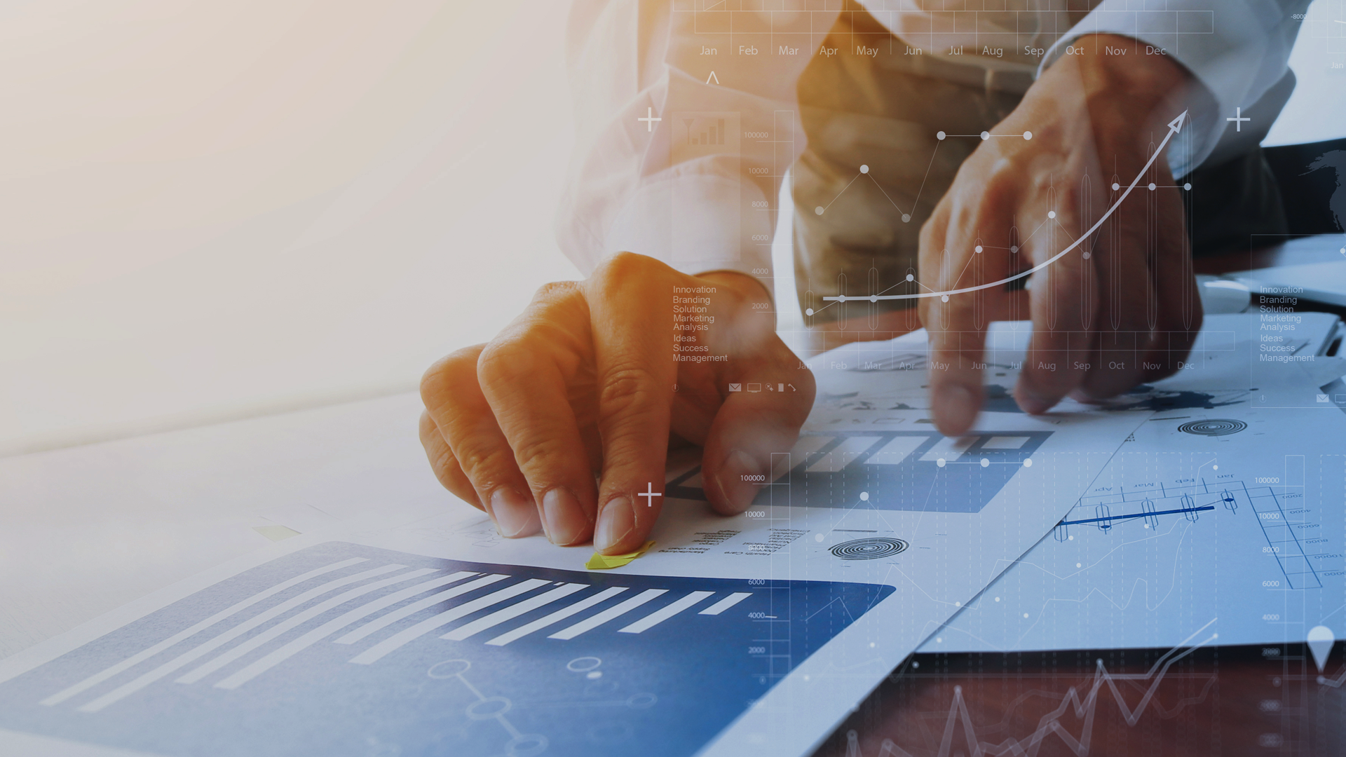 The photo shows a man leaning against a desk top, his hands are resting on chart prints, the photo also has watermarks applied also showing charts, white and blue color scheme with a slight warm glow at the top of the photo, office style. The photo is the cover graphic for a blog post by Transition Technologies PSC titled ITSM, the most common challenges during implementation.