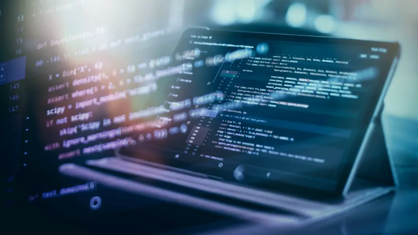 A tablet shows code with digital effects, symbolizing programming or tech development.