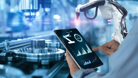 Engineer monitoring robotic machinery on a tablet.