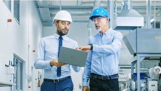 Person using a tablet to monitor and control industrial systems with data analytics and AI interface         overlays, set against a background of a modern factory or power plant.