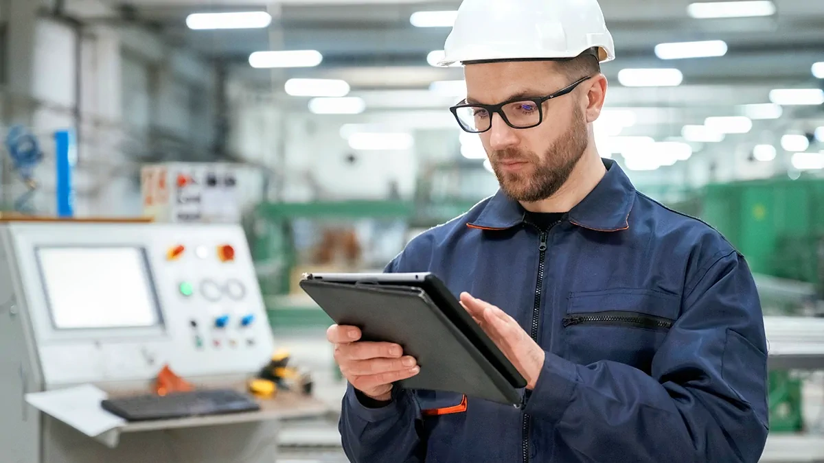 Person, die ein Tablet zur Überwachung und Steuerung von Industriesystemen mit Datenanalyse und KI-Schnittstelle verwendet Overlays, vor dem Hintergrund einer modernen Fabrik oder eines Kraftwerks.