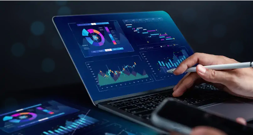 Analyst working on a laptop with interactive dashboards and data charts.