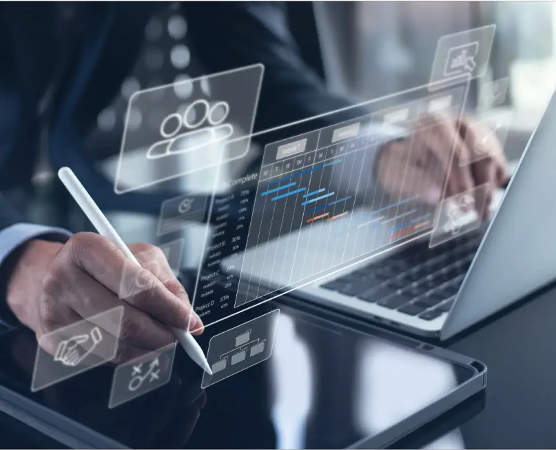 A person working on a tablet and laptop, analyzing project charts and managing tasks.
