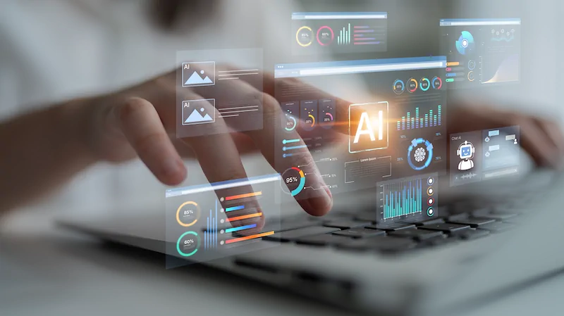 Hands typing on a laptop with holographic AI dashboards, charts and analytics overlays floating above the keyboard.